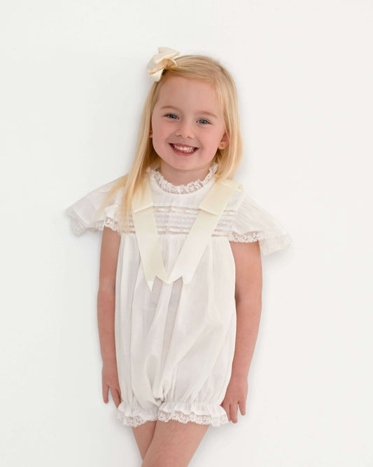 Young girl wearing a white dress with a large bow on a white background