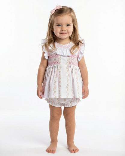 Young girl wearing a white dress with floral patterns on a white background