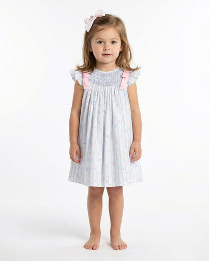 Young girl wearing a white dress with pink accents on a white background