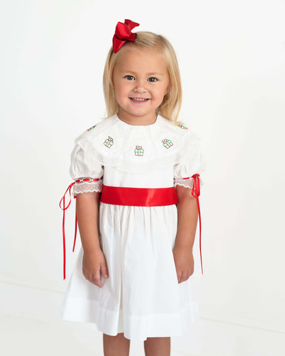 Young girl wearing a white dress with red accents on a white background