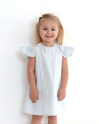 Young girl wearing a white dress with ruffled sleeves on a plain background