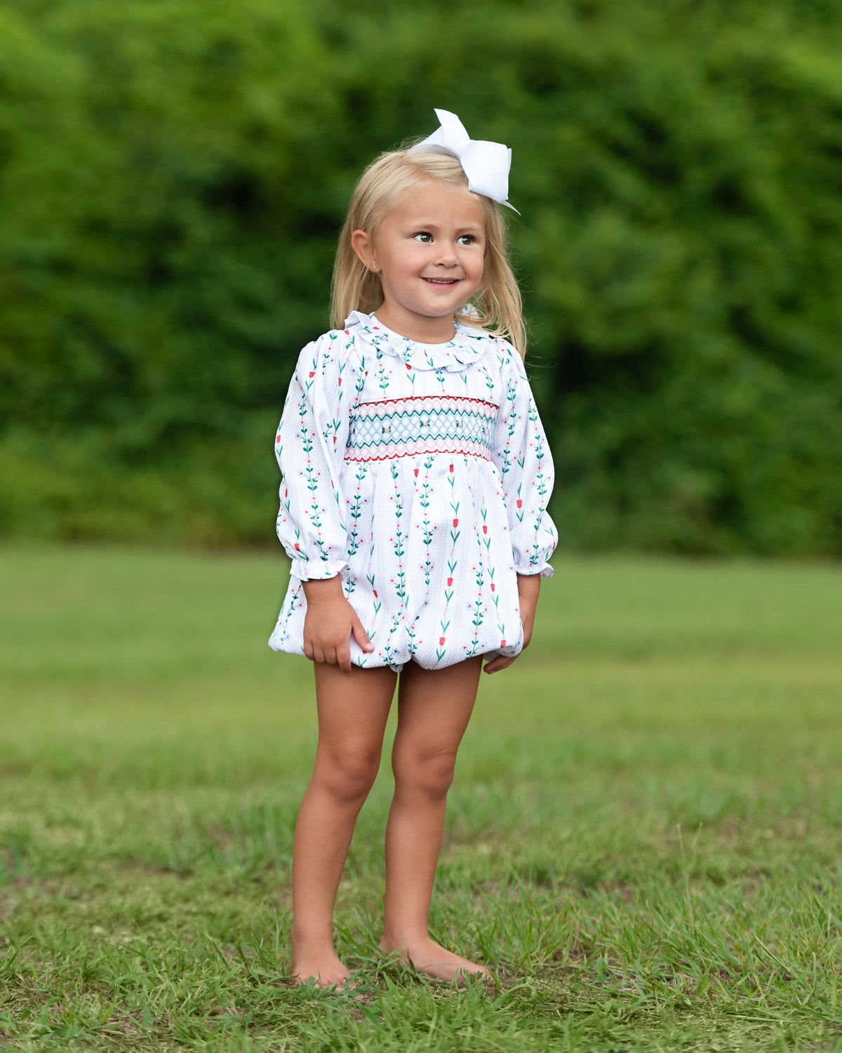 Young girl wearing  floral bubble outfit with some green and red designs.
