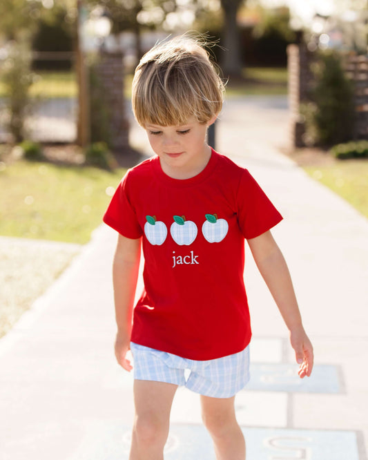 boy in apple outfit standing on a sidewalk looking down