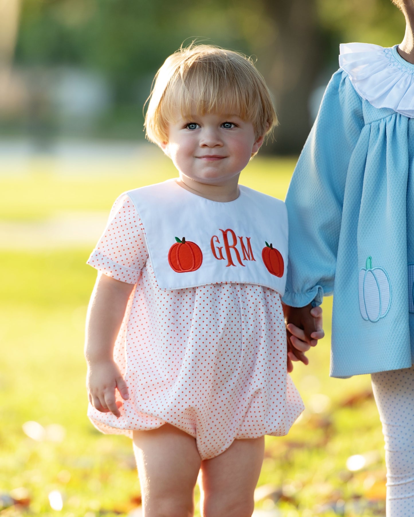 boy wearing a bubble with pumpkin designs and 'GRM' text outdoors.