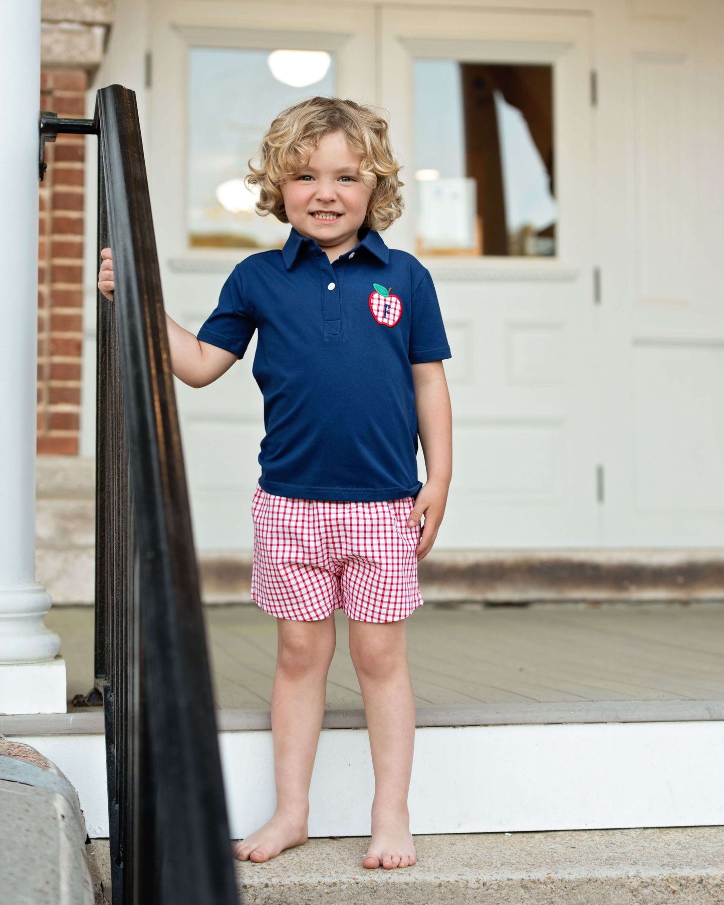 boy wearing navy shirt with an apple and red shorts