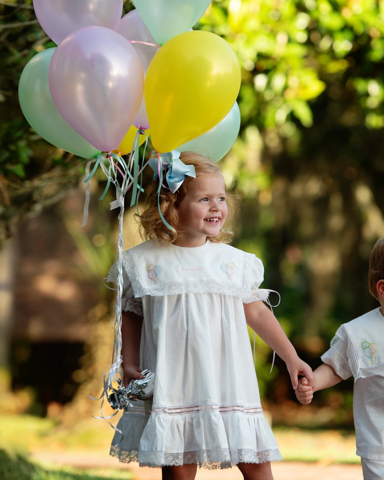 Child holding balloons outdoors with a blurred natural background