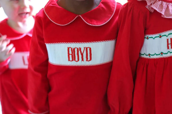 Children wearing red custom smocked outfits personalized with a name