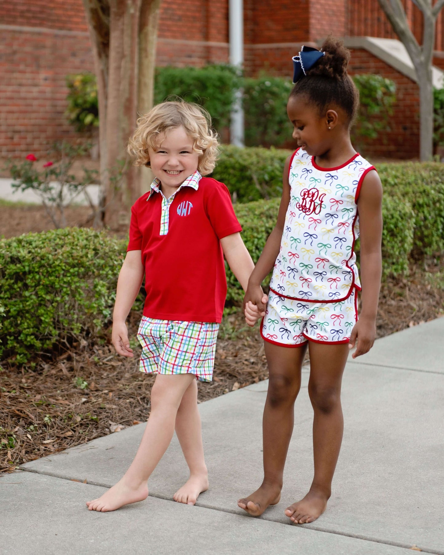 children standing on sidewalk holding hands wearing colorful outfits 