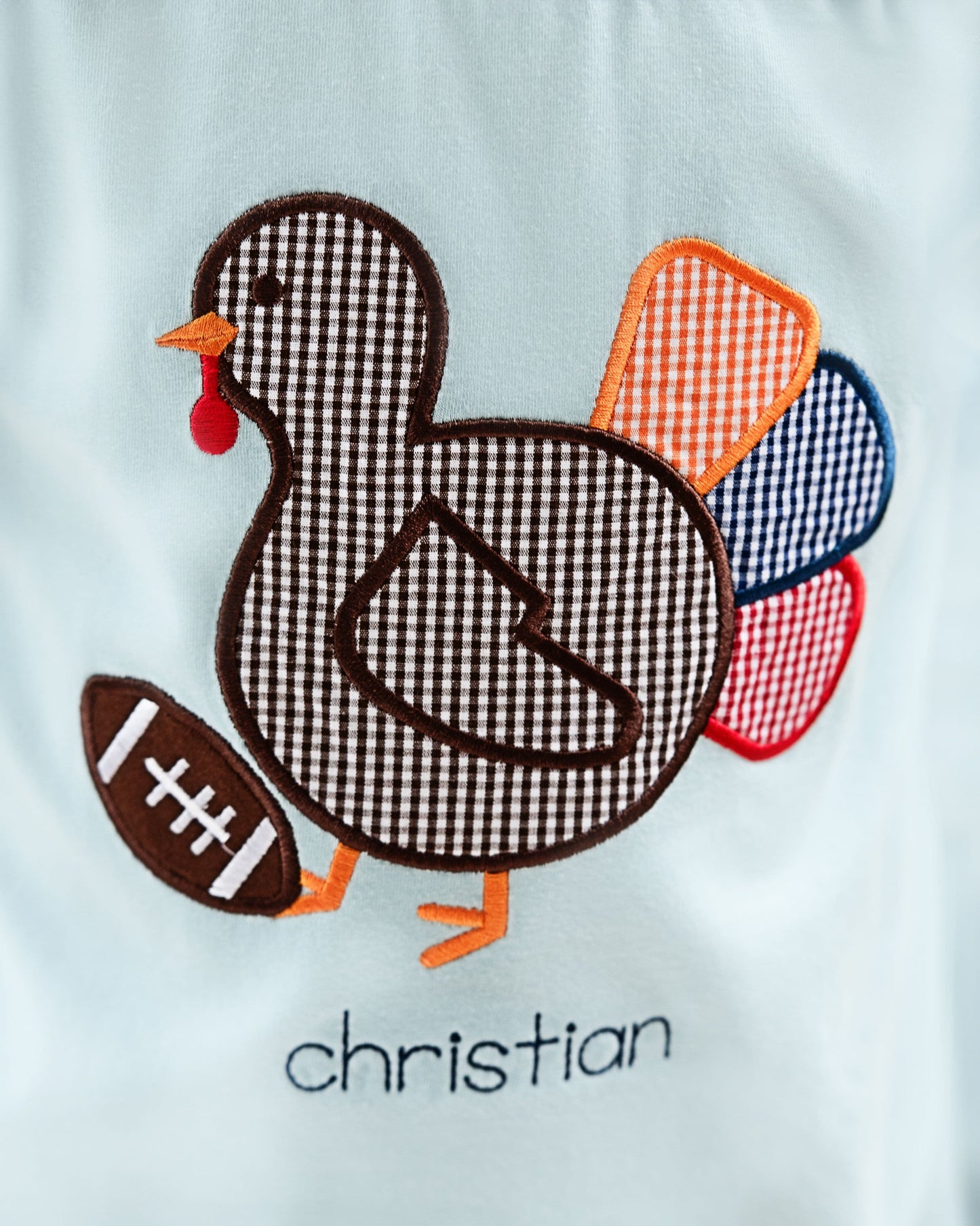 close up of blue shirt with turkey and football design with monogram "christian"