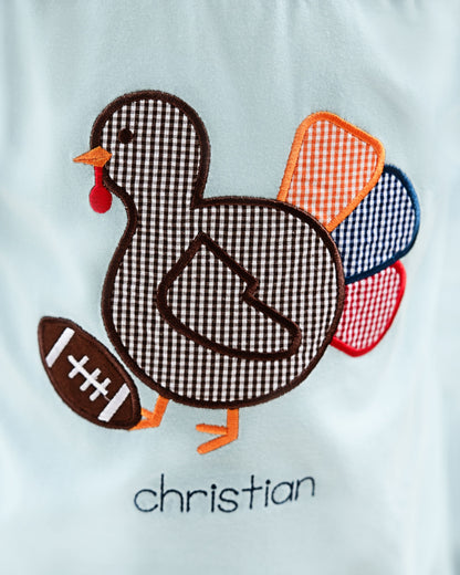 close up of blue shirt with turkey and football design with monogram "christian"