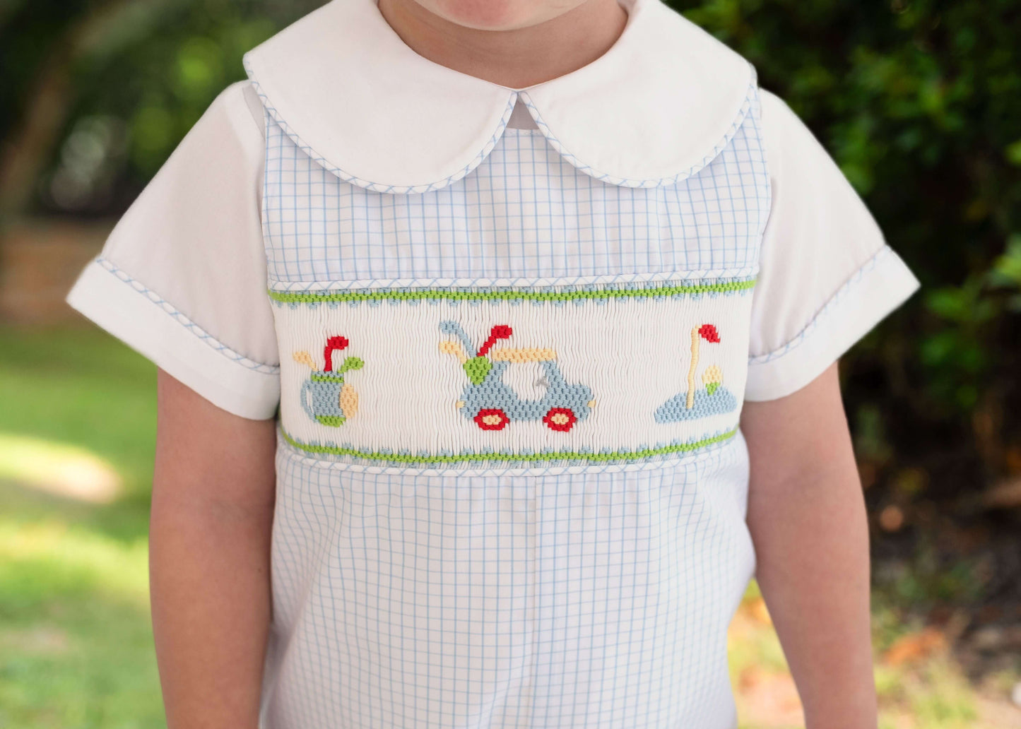 close up of outfit with smocked golf motif and a white undershirt