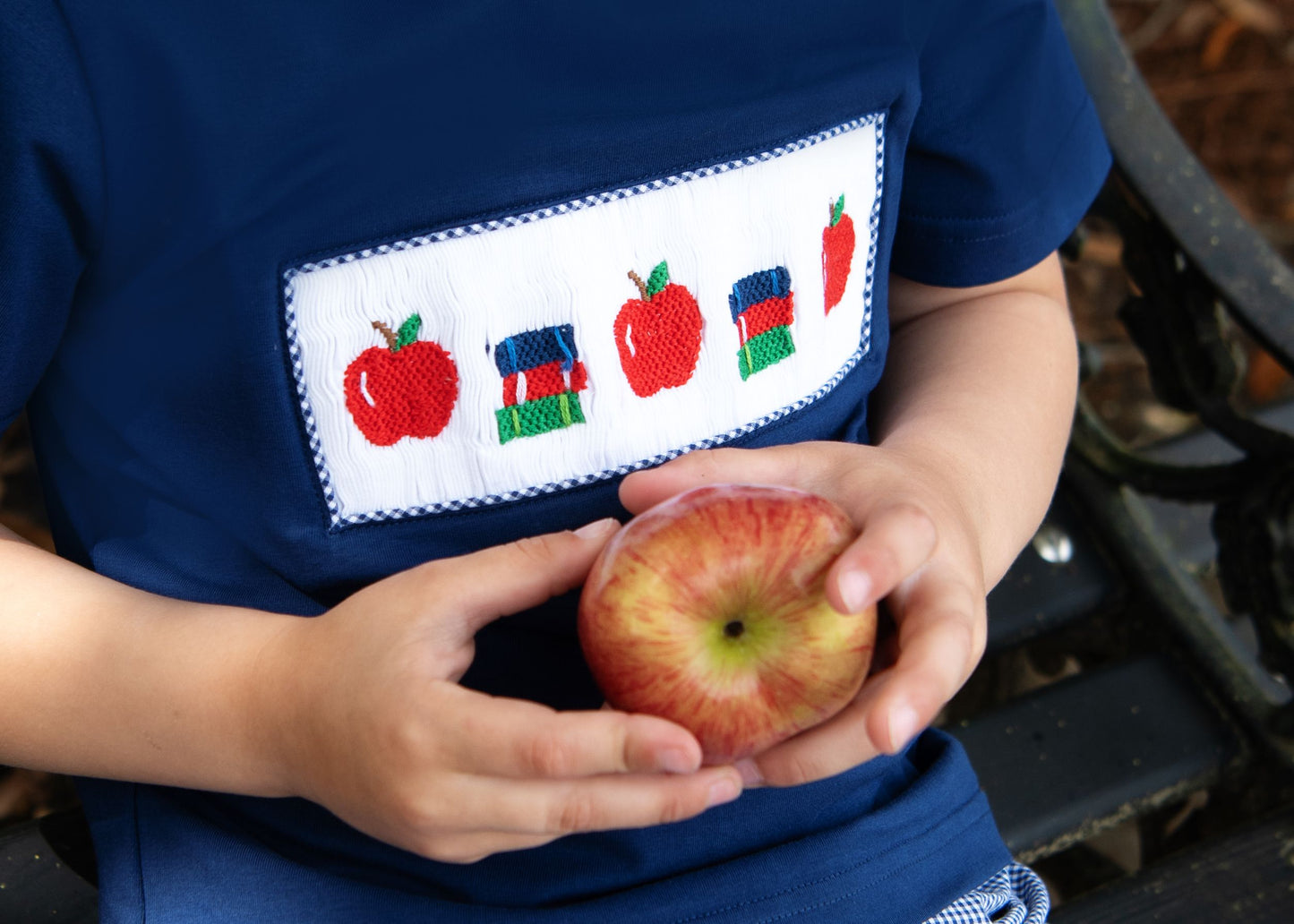 close up smocked of apples and books on a navy shirt