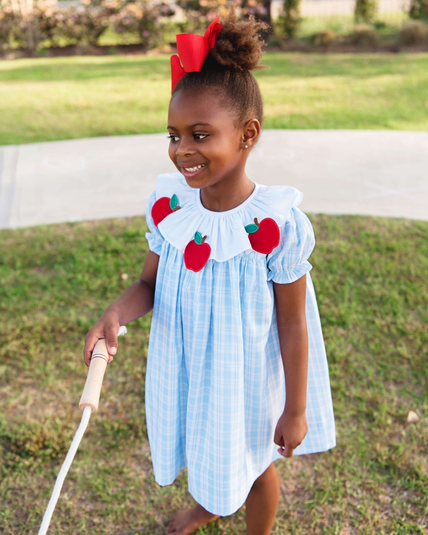 girl wearing blue dress with apples holding a jump rope