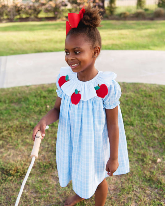 girl wearing blue dress with apples holding a jump rope