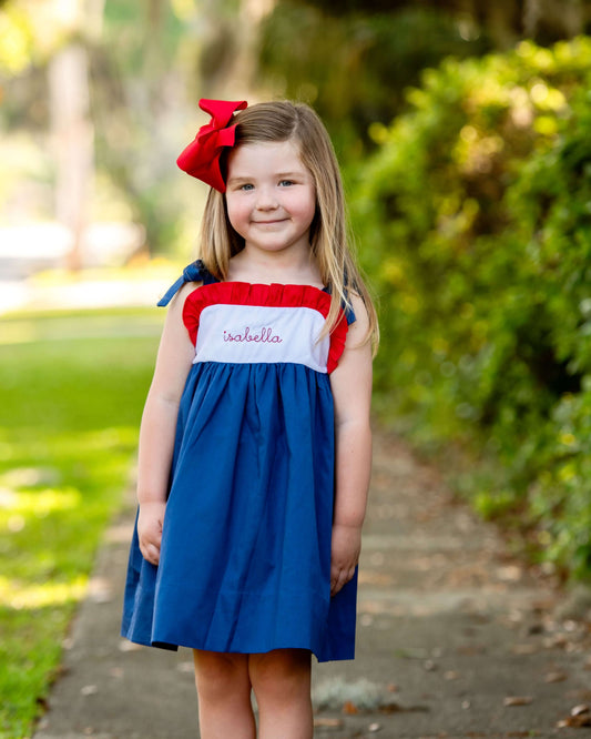 girl wearing red, white and blue dress with a red bow 