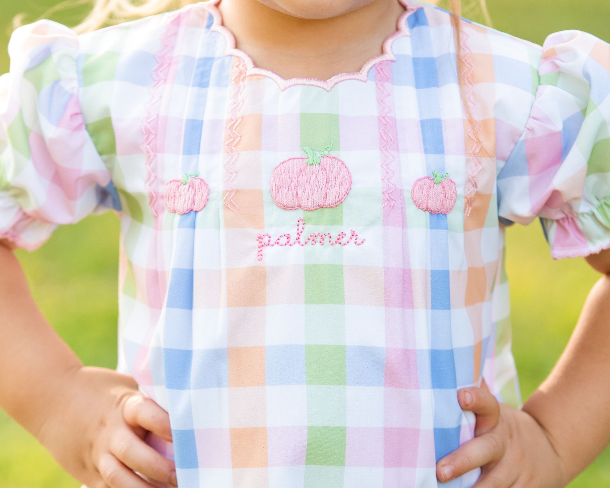 girls dress with checkered pattern and embroidered pumpkins on a blurred green background