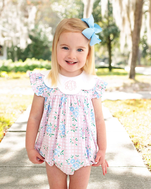 little girl modeling a floral bubble standing outside with a blue bow in her hair