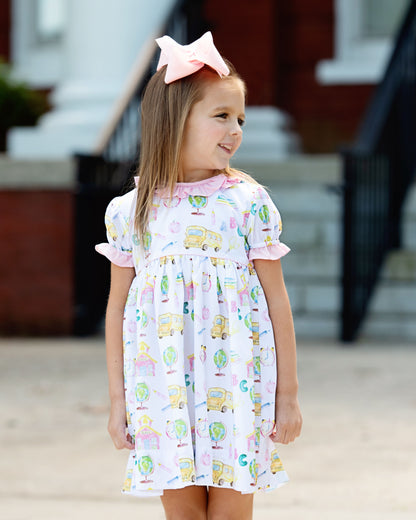 little girl wearing a back to school dress standing outside