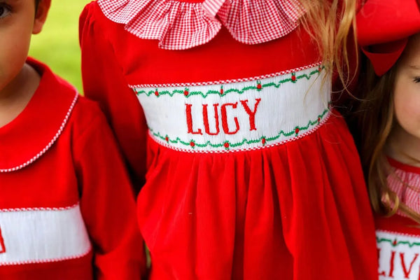 Red custom smocked dress personalized with a child's name, surrounded by children