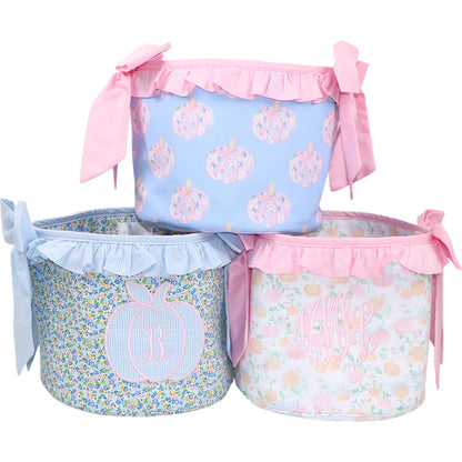 Three decorative storage bins with floral patterns and pink ribbons on a white background