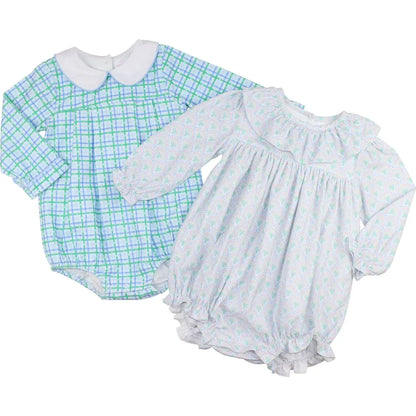 Two baby outfits: a green checkered romper and a white dress with blue floral pattern on a white background.