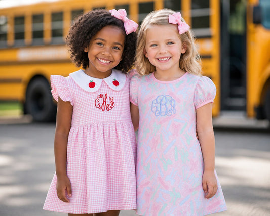 two young girls in back to school clothes standing in front of a bus