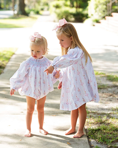 two young girls wearing matching smocked nutcracker bubble and dress