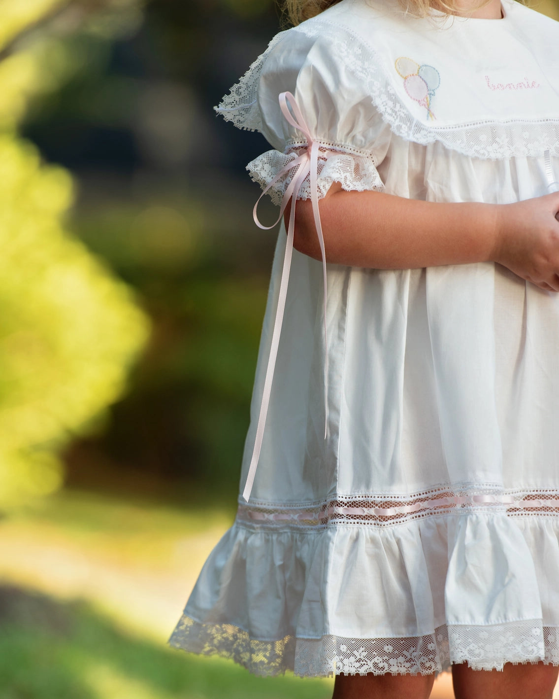 White lace dress worn by a person with a blurred natural background