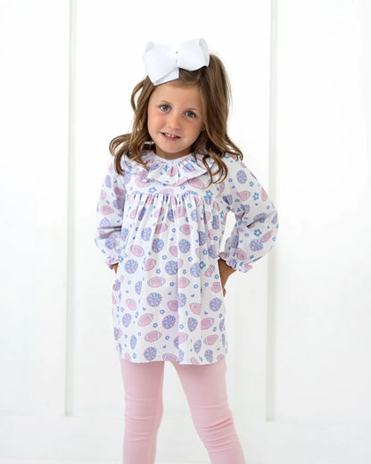 Young girl wearing a floral dress and pink leggings with a white background