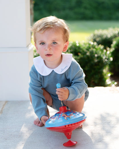 young boy playing outside with a toy wearing a bluish grey sweater diaper set with a monogram on the collar