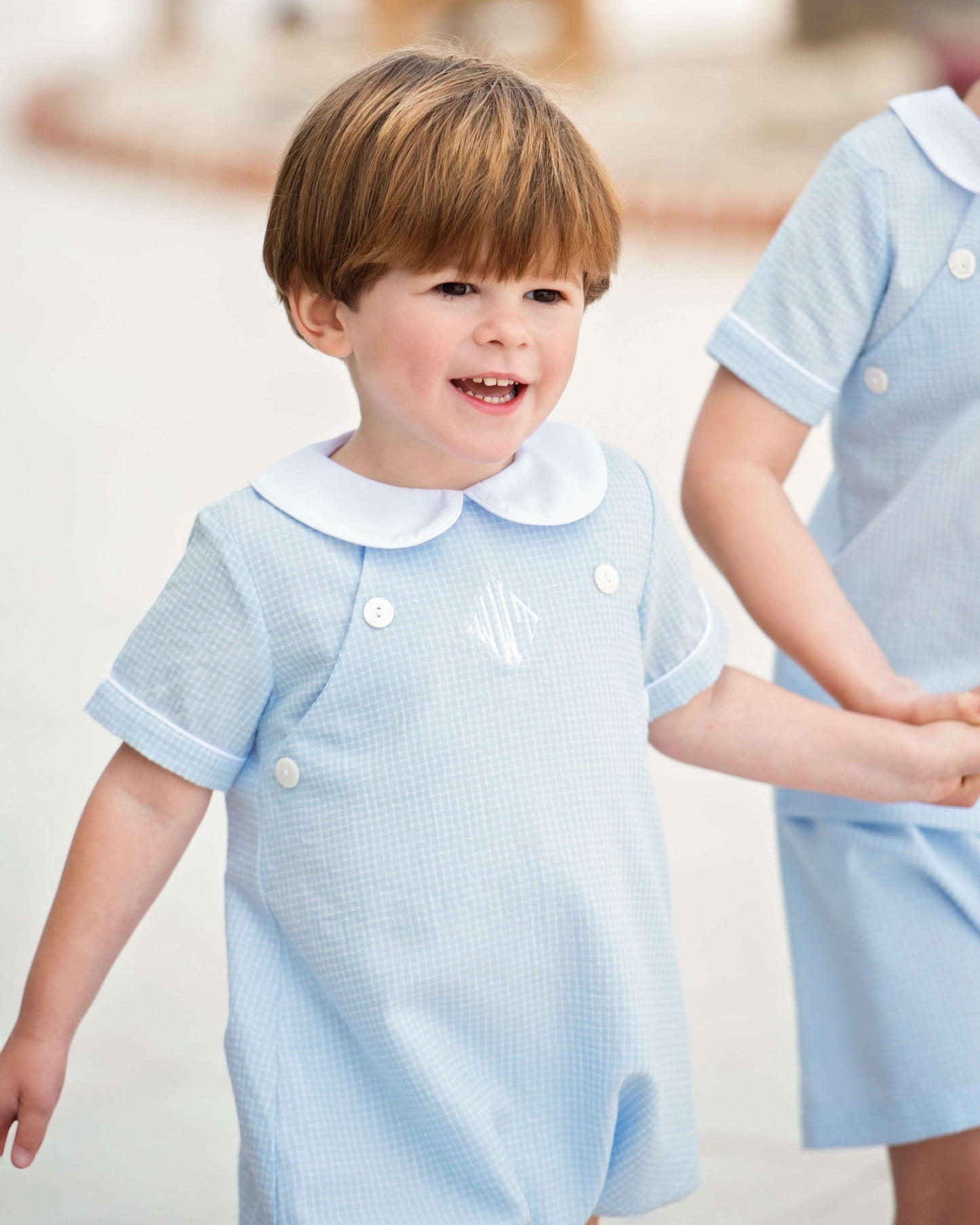 young boy wearing a light blue bubble with button detail