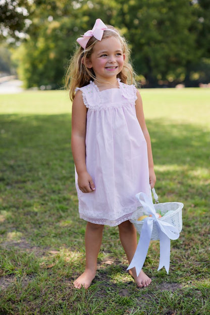 Girl wearing pink embroidered dress outdoors holding Easter basket, full length view