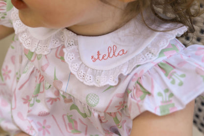 young girl wearing a golf print bubble with a monogrammed name on the eyelet collar